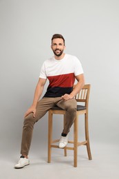 Photo of Handsome man sitting on stool against light grey background