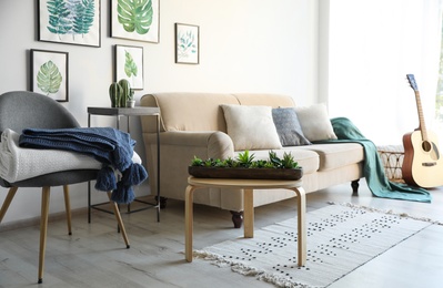 Stylish living room interior with comfortable sofa, chair and plaids