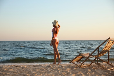 Photo of Young woman near deck chair on beach