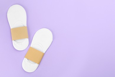 Photo of Soft cotton socks on lilac background, flat lay. Space for text