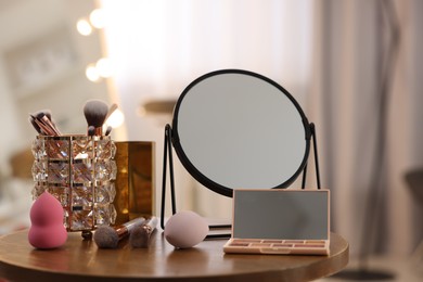 Different beauty products and mirror on wooden table in makeup room