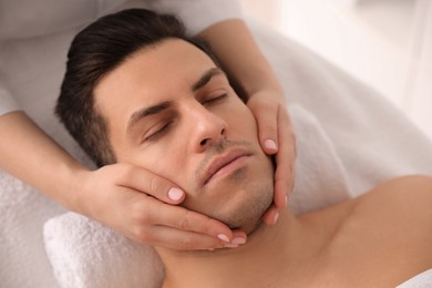 Photo of Man receiving facial massage in beauty salon, above view