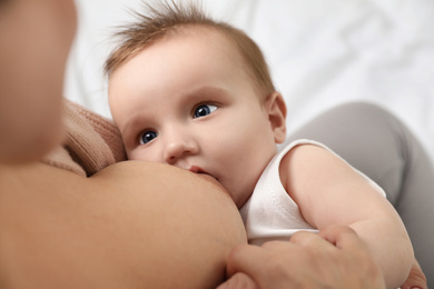 Photo of Woman breastfeeding her little baby on blurred background, above view