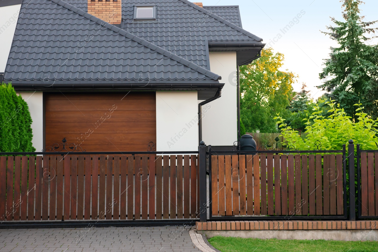 Photo of House and trees behind beautiful wooden fence outdoors