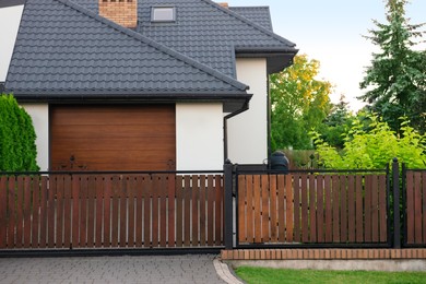 Photo of House and trees behind beautiful wooden fence outdoors