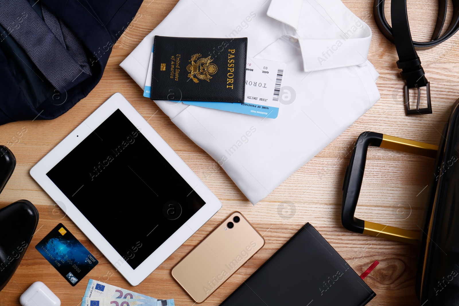 Photo of Business trip stuff and suitcase on wooden surface, flat lay