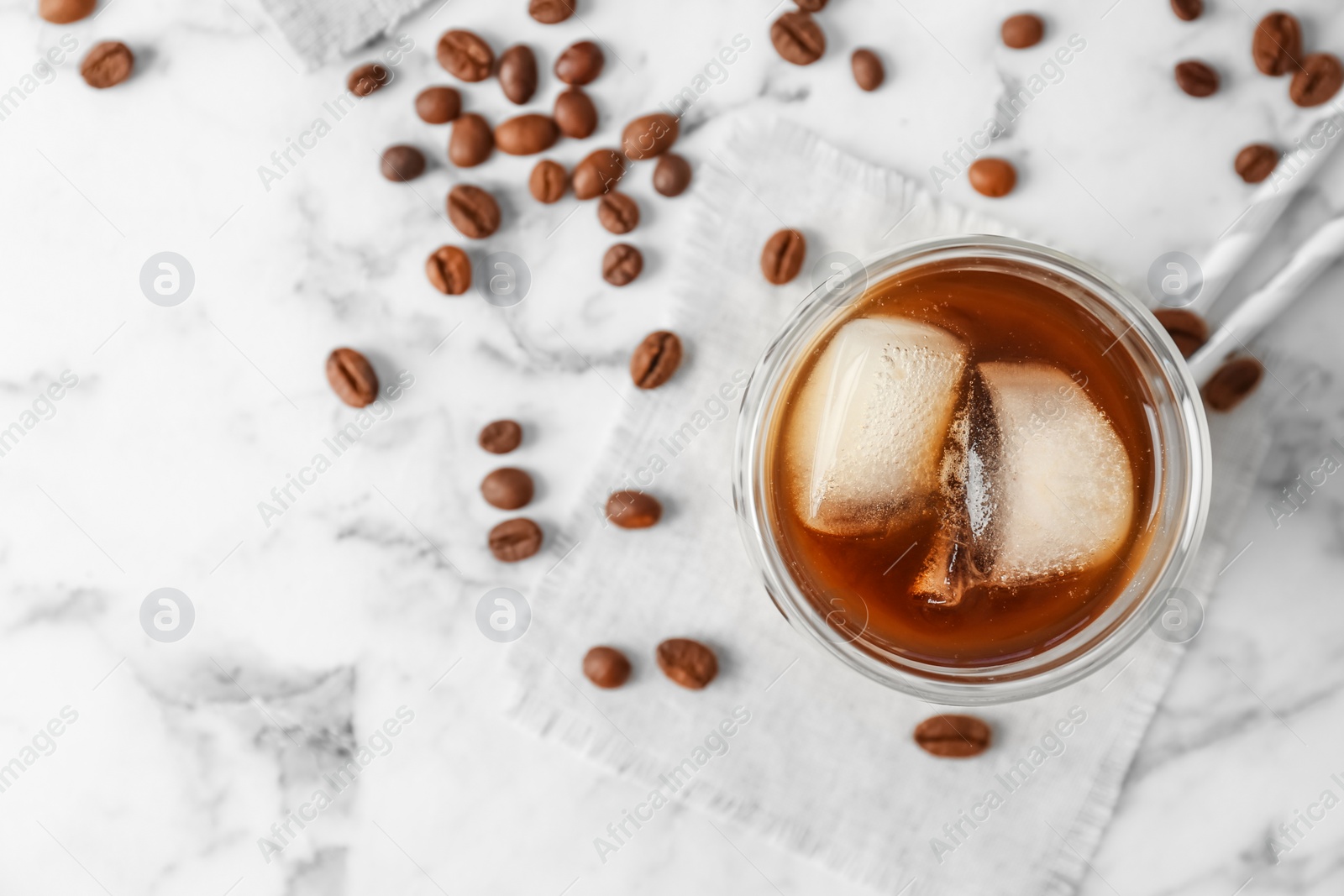 Photo of Glass with cold brew coffee and beans on light background, top view