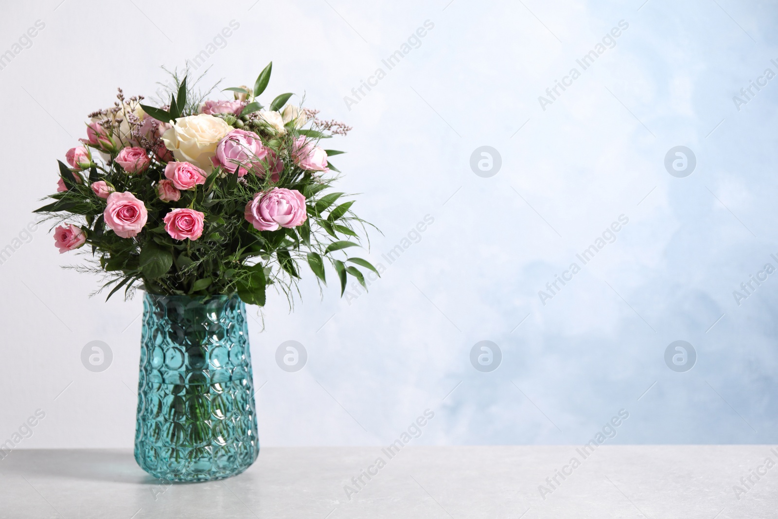 Photo of Beautiful bouquet with roses on light table. Space for text