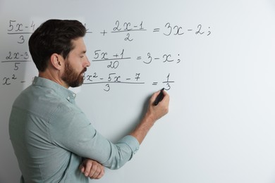 Photo of Mature teacher explaining mathematics at whiteboard in classroom