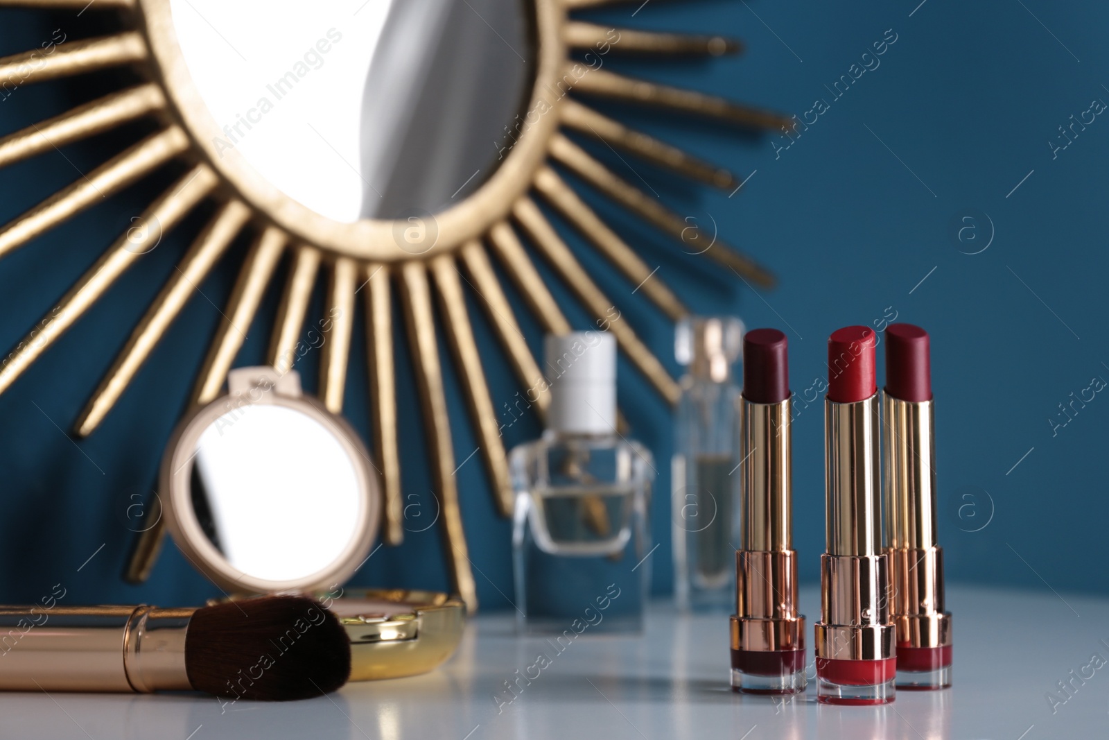 Photo of Bright lipsticks in gold tubes on dressing table, space for text