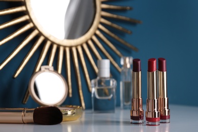 Photo of Bright lipsticks in gold tubes on dressing table, space for text
