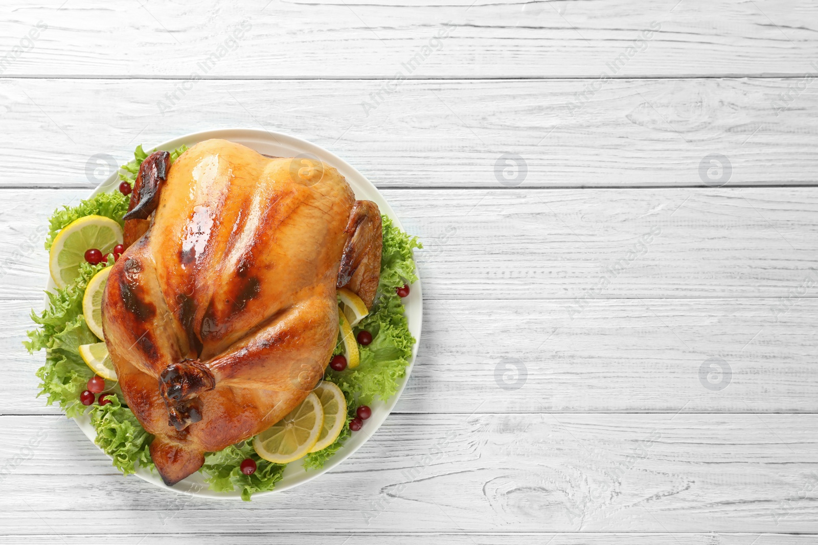 Photo of Delicious roasted turkey on wooden table, top view. Space for text