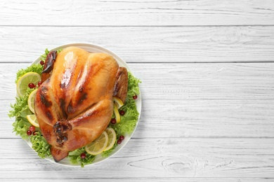 Photo of Delicious roasted turkey on wooden table, top view. Space for text