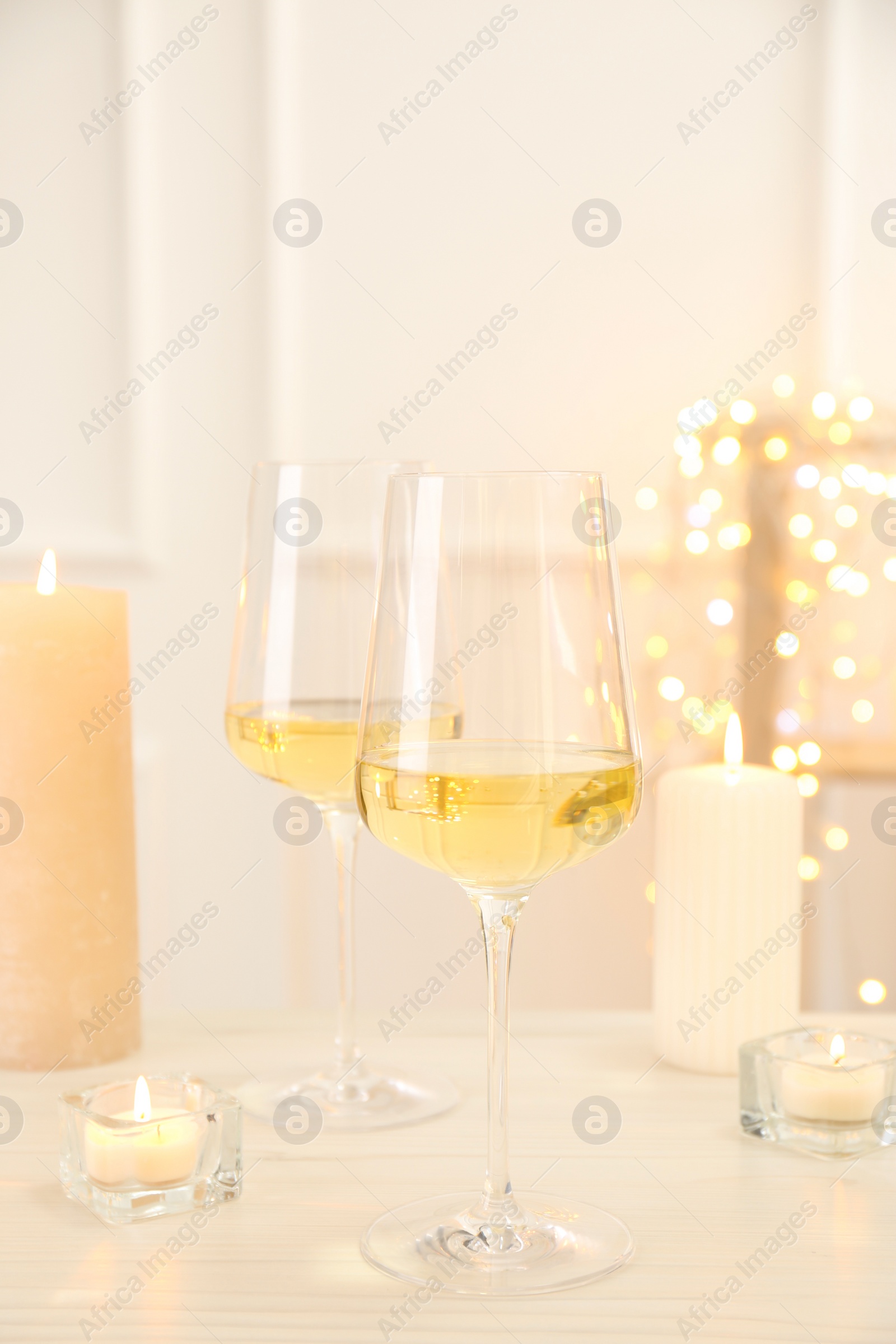 Photo of Glasses of wine and candles on wooden table