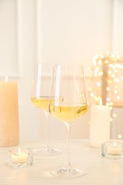 Glasses of wine and candles on wooden table