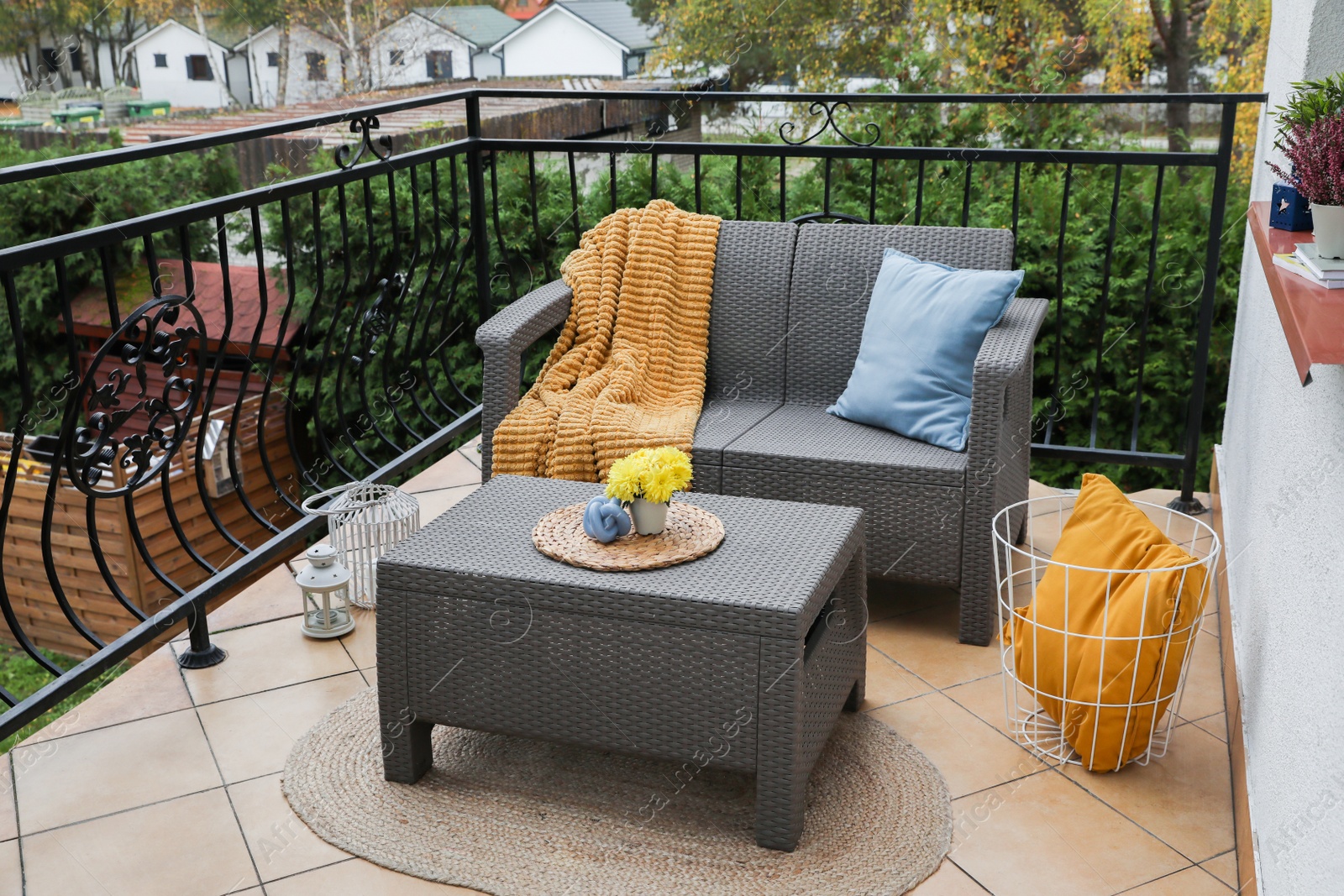 Photo of Colorful pillows, soft blanket and yellow chrysanthemum flowers on rattan garden furniture outdoors