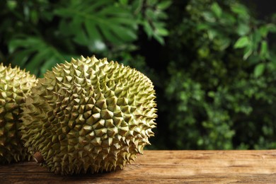 Photo of Ripe durians on wooden table against blurred background. Space for text