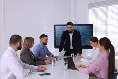 Photo of Business trainer near interactive board in meeting room during presentation