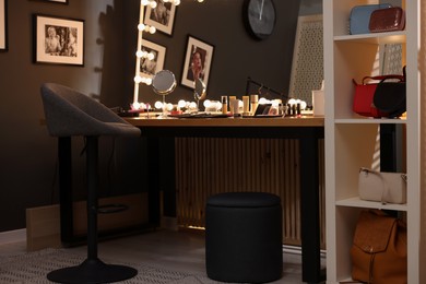 Photo of Makeup room. Stylish mirror on dressing table with different beauty products