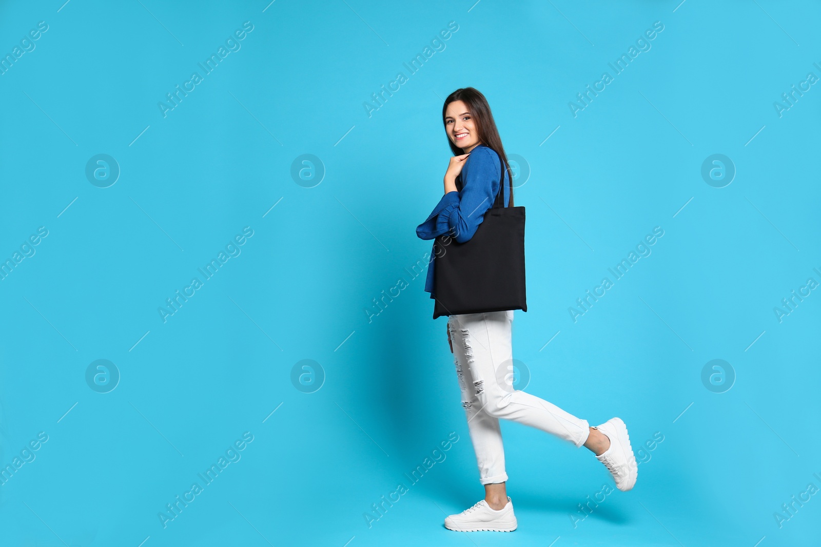 Photo of Beautiful young woman with stylish blank eco bag against color background, space for text