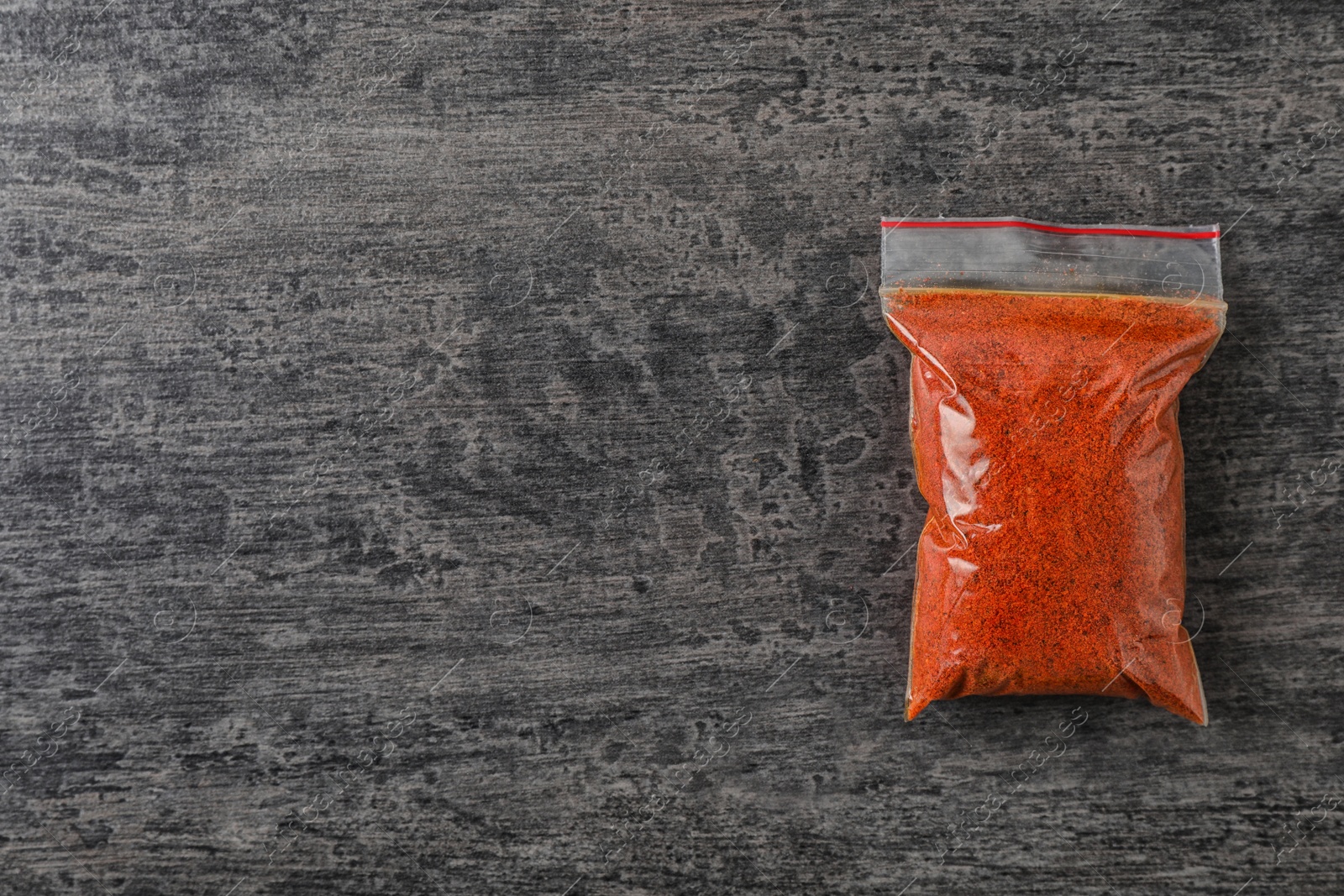 Photo of Plastic bag with spice on grey background, top view