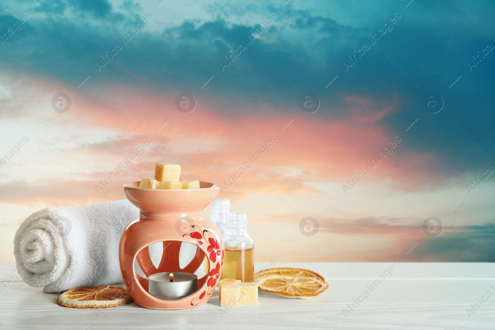 Image of Composition with aroma lamp on white wooden table outdoors at sunset, space for text