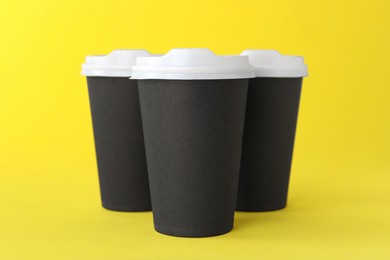Paper cups with white lids on yellow background. Coffee to go