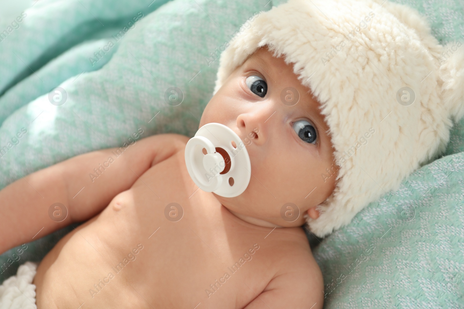 Photo of Cute little baby with pacifier lying on soft blanket