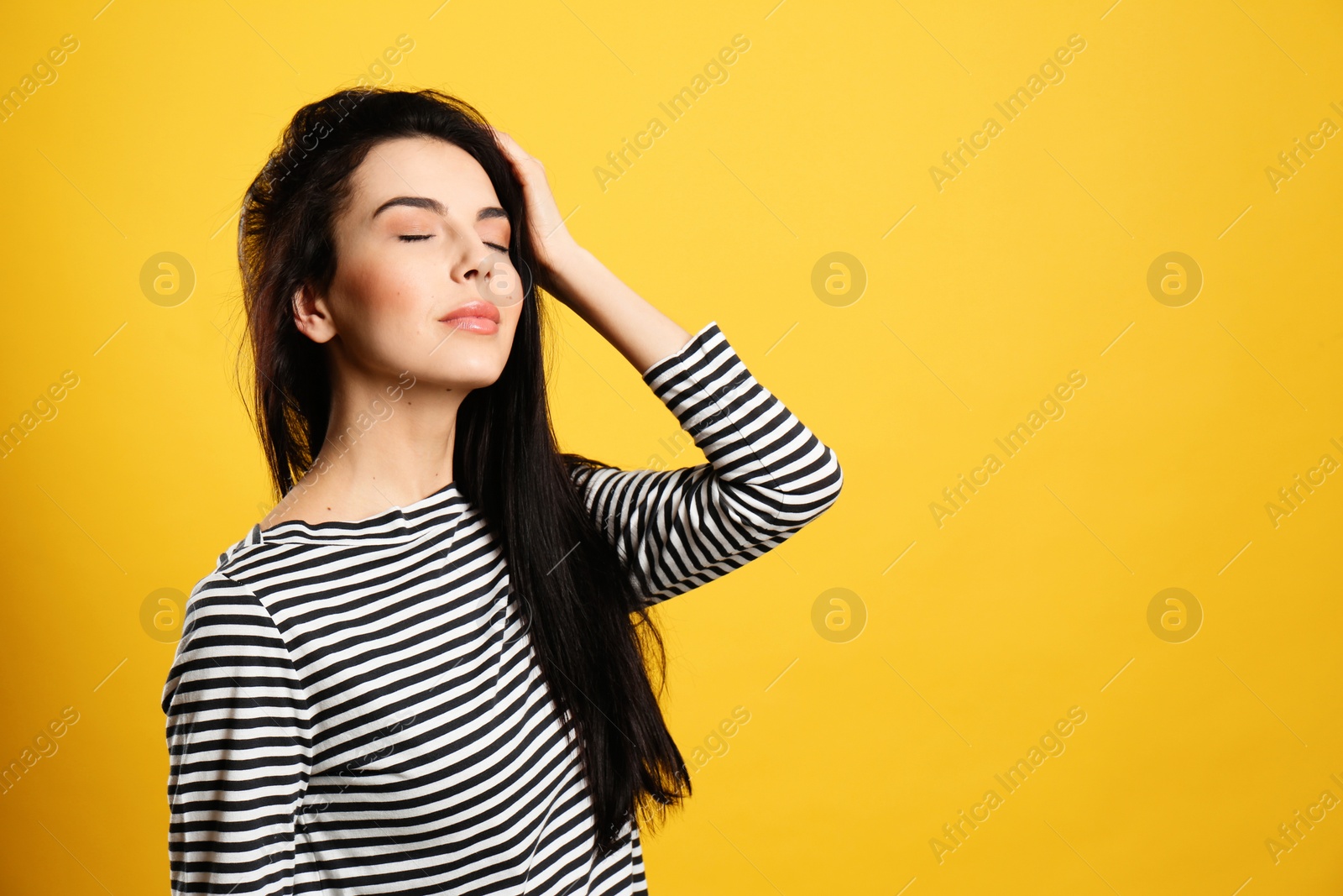 Photo of Portrait of young woman with beautiful black hair on yellow background, space for text