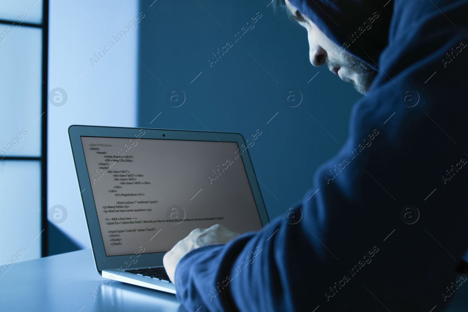 Photo of Man using laptop in dark room. Criminal offence