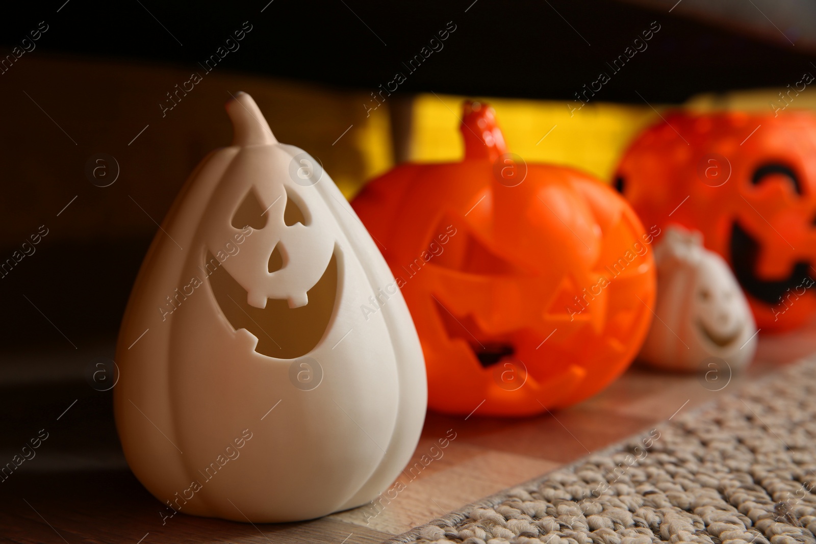 Photo of Different pumpkin shaped candle holders on floor in room