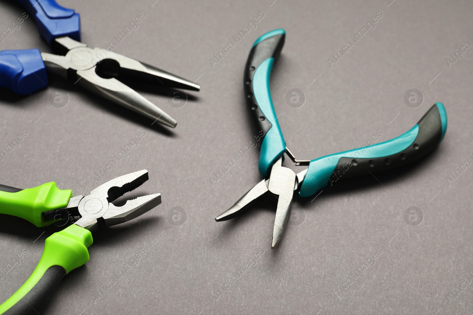 Photo of Different pliers on grey background, closeup view