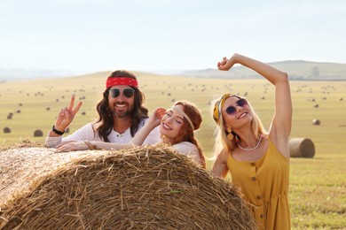 Happy hippie friends near hay bale in field