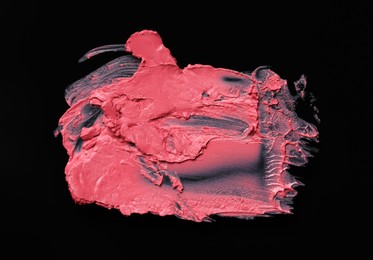 Smears of pink lipstick on black background, top view