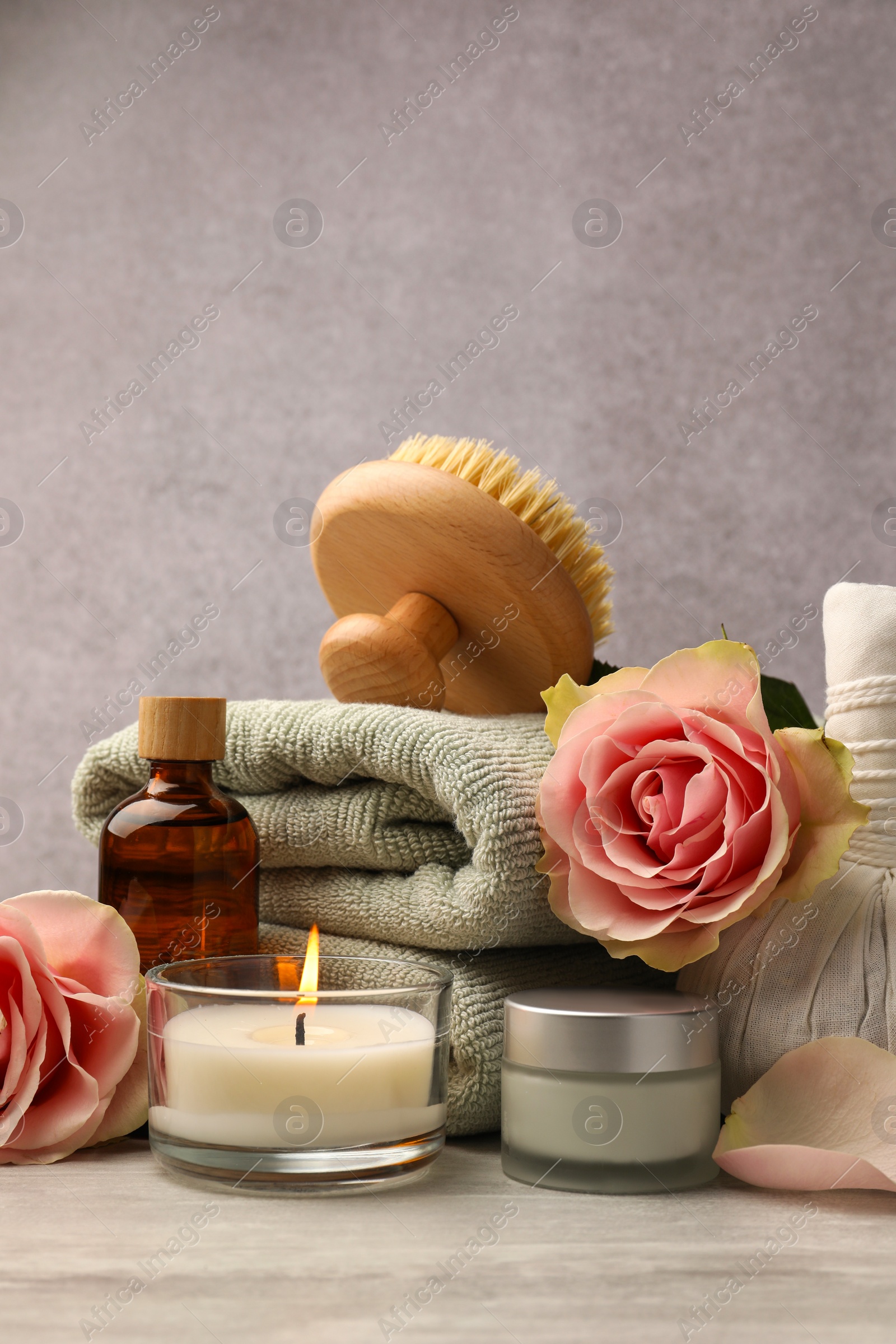 Photo of Composition with spa products, roses and candle on grey wooden table