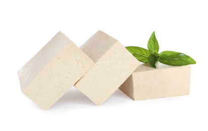 Photo of Blocks of delicious raw tofu with basil on white background