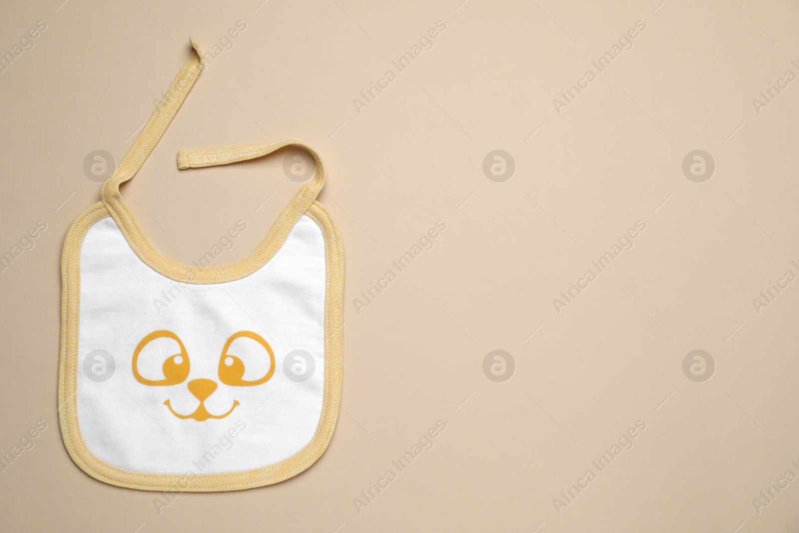 Photo of New baby bib on beige background, top view. Space for text