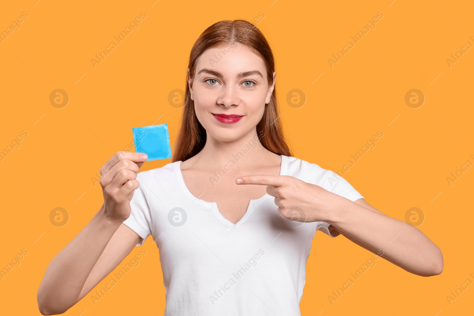 Photo of Woman holding condom on yellow background. Safe sex