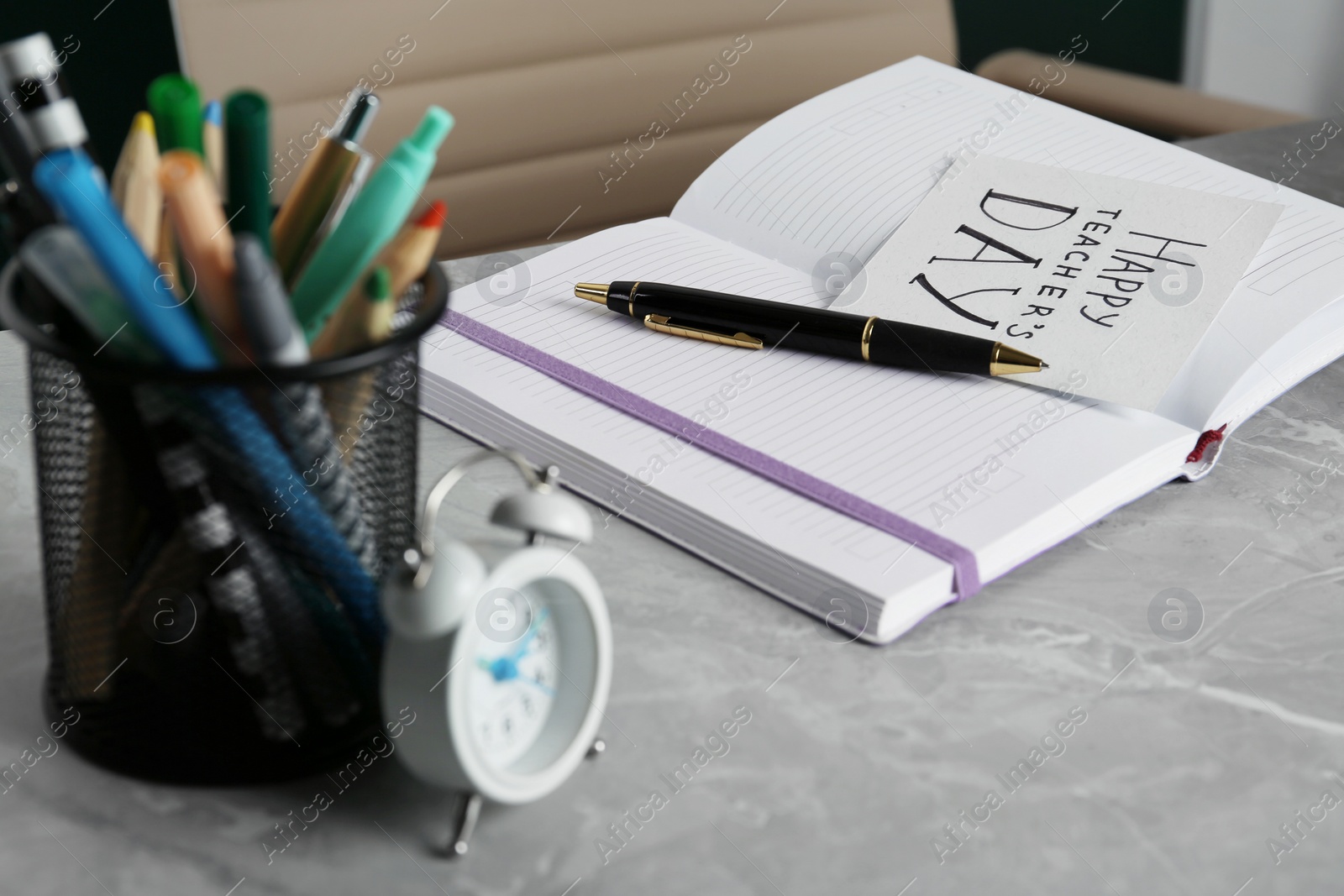 Photo of Paper with inscription HAPPY TEACHER'S DAY, notebook and stationery on grey stone table