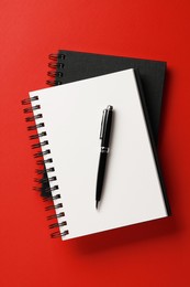 Photo of Notebooks and pen on red background, top view