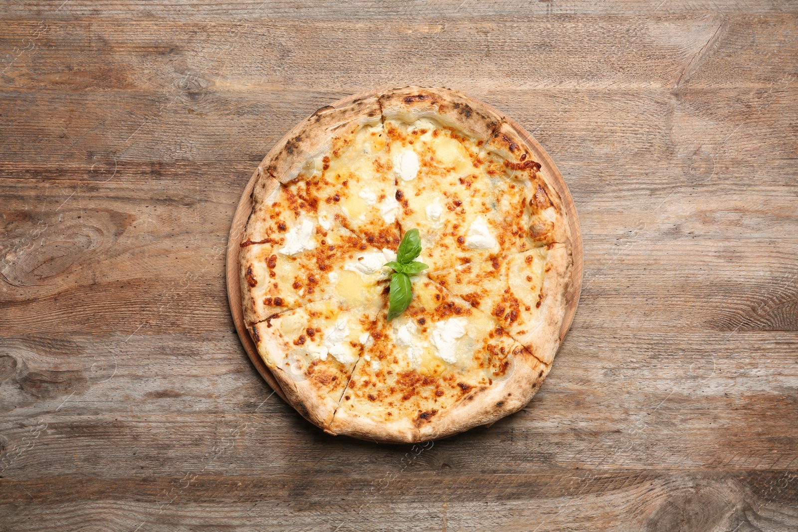 Photo of Delicious pizza with cheese and basil on wooden background, top view