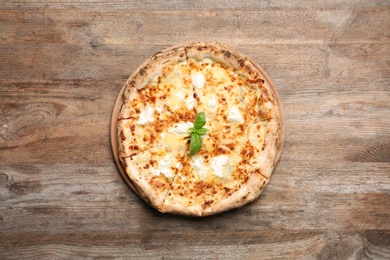 Photo of Delicious pizza with cheese and basil on wooden background, top view