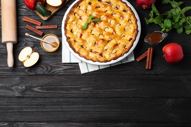 Flat lay composition with fresh traditional apple pie on black wooden table. Space for text