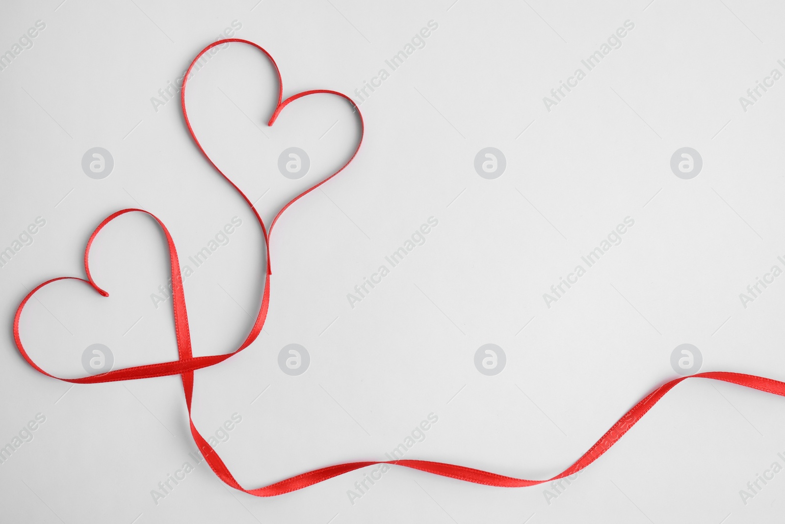 Photo of Hearts made of red ribbon on white background, top view. Valentine's day celebration