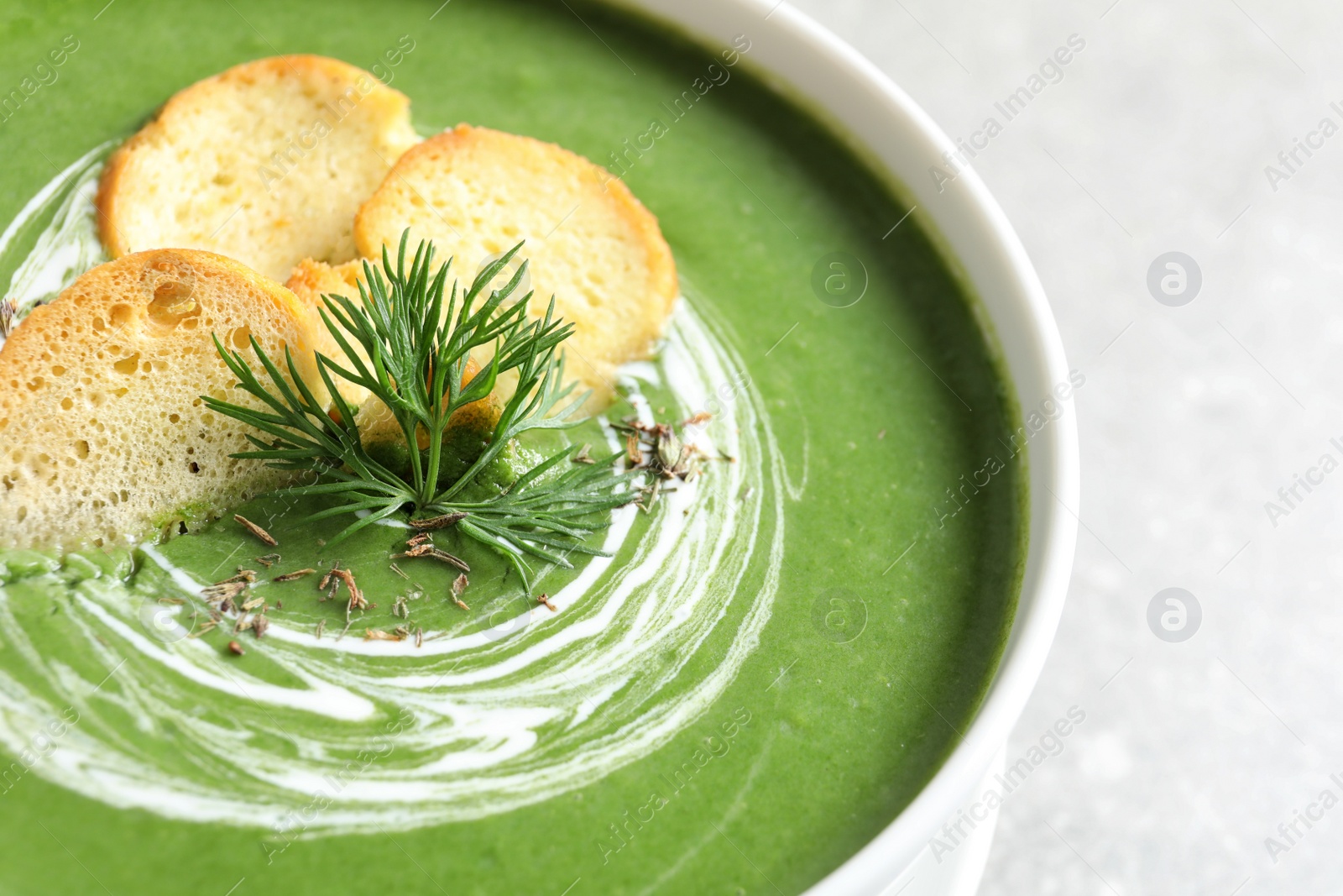 Photo of Fresh vegetable detox soup with croutons in dish on table, closeup