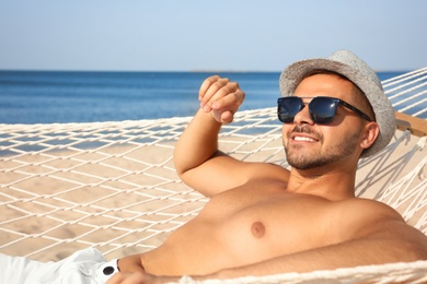 Photo of Young man relaxing in hammock on beach