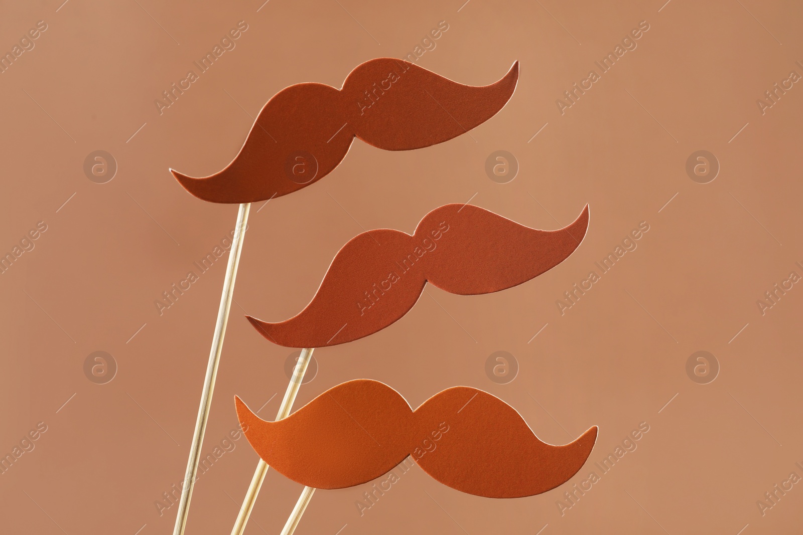 Photo of Fake paper mustaches party props on light brown background