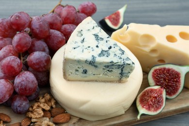 Different types of delicious cheeses and snacks on wooden table, closeup