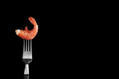 Photo of Fork with delicious shrimp on dark background