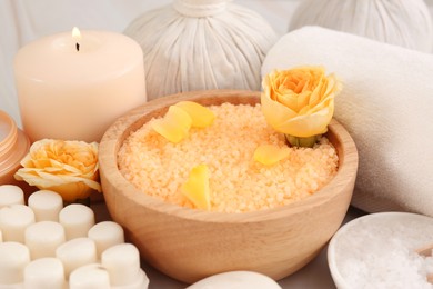 Photo of Sea salt, different spa products and beautiful rose on table, closeup